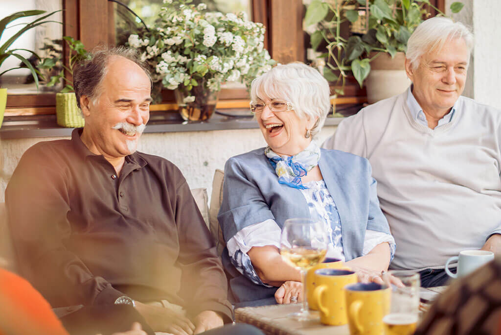 Three seniors sitting outdoors and laughing